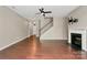 Open concept living room with fireplace, ceiling fan, hardwood floors, and staircase at 9551 Glenburn Ln, Charlotte, NC 28278