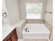 Bathtub featuring tile surround, a window, and modern fixtures at 9551 Glenburn Ln, Charlotte, NC 28278