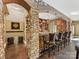 A basement bar with stone arch, wood counter, and leather stools providing a cozy spot for drinks at 1012 Shippon Ln, Waxhaw, NC 28173
