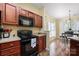 Well-equipped kitchen features a black stove, microwave, dark wood cabinets, and hardwood flooring at 121 Talbert Town Loop, Mooresville, NC 28117