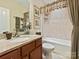 Well-lit bathroom featuring a granite vanity, decorative mirror, and bathtub with neutral-toned tile surround at 1231 Restoration Dr, Marvin, NC 28173