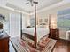 A bright main bedroom with a canopy bed, tray ceiling, and hardwood floors at 1231 Restoration Dr, Marvin, NC 28173