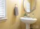 Charming powder room with pedestal sink, an oval mirror, and natural light from the window at 126 Pointer Se Ct, Concord, NC 28025