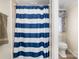 Bathroom shower-tub with blue striped curtain and a window providing natural light to the commode at 140 Misty Ln, Rockwell, NC 28138