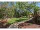 Lush backyard with mature trees, green lawn, mulch beds, a charming white deer statue, and a pergola at 1427 Doe Ridge Ln, Fort Mill, SC 29715