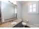 Modern bathroom with granite countertop, gray cabinets, a square mirror, and a shuttered window at 1550 Matthew Mcclure Cir, Davidson, NC 28036