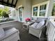 Cozy front porch with outdoor seating, decorative pillows, and a side table with pink flowers at 1550 Matthew Mcclure Cir, Davidson, NC 28036
