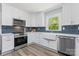 Modern kitchen with white cabinets, blue subway tile backsplash, stainless steel appliances, and farmhouse sink at 166 Franklin Nw Ave, Concord, NC 28025