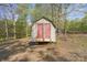 A white wood outbuilding with faded red doors for storing your mower and garden tools sits in the yard at 170 Dusty Loop Dr, Mount Gilead, NC 27306