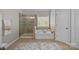Bright bathroom featuring a soaking tub, glass shower, and tile flooring at 1809 Robbins Meadows Dr, Waxhaw, NC 28173
