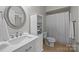 Bright bathroom featuring a white vanity with storage, a modern round mirror, and tiled floors at 1809 Robbins Meadows Dr, Waxhaw, NC 28173