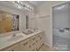 Bright bathroom featuring a double sink vanity, large mirror, and a doorway view of the tub at 1910 York Hwy, York, SC 29745