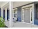 Inviting front porch with white columns, seating, and a gray front door with sidelights and transom window at 235 Boxelder Rd, Clover, SC 29710