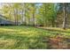 Expansive backyard with lush greenery and mature trees, featuring a wooden deck and storage shed at 2371 Lazy Oak Dr, Lancaster, SC 29720
