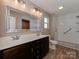 Bathroom featuring double sink vanity, large mirror, and walk-in shower with white tiled walls at 317 Contentment Dr, Locust, NC 28097