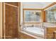 Bathroom featuring a soaking tub with an adjacent shower and views of a wooded lot at 3605 Ridgetop Rd, Sherrills Ford, NC 28673