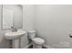 Powder room features a pedestal sink, white toilet, and brushed gold fixtures at 7117 Brookview Ln, Sherrills Ford, NC 28673