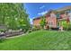 Manicured lawn and professionally landscaped backyard with stone fireplace, seating area, and mature trees at 727 Bluff Loop Rd, Rock Hill, SC 29730