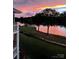 Serene lake view featuring a manicured lawn and a captivating sunset backdrop at 7829 Village Harbor Dr, Cornelius, NC 28031