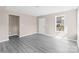 Bright living room featuring gray wood-look floors and several windows for natural light. Backdoor on right wall at 8722 Moody Rd, Charlotte, NC 28215