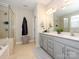 Bright bathroom featuring gray cabinets, dual sinks, a glass shower enclosure and soaking tub at 10024 Fox Trotter Ln, Midland, NC 28107