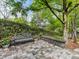 Backyard patio with stone pavers, seat wall, metal bench, and lush landscaping at 10626 Newberry Park Ln, Charlotte, NC 28277