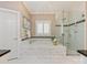 Elegant bathroom with marble tile, soaking tub, glass shower, and plantation shutters at 10626 Newberry Park Ln, Charlotte, NC 28277