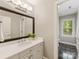 Bathroom with a white vanity, large mirror, and views to the green outdoors at 10626 Newberry Park Ln, Charlotte, NC 28277