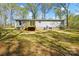 The home's rear shows light siding and a wooden deck, set in a yard surrounded by trees at 110 Matthew Dr, Kings Mountain, NC 28086