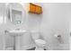 Cozy bathroom with pedestal sink, toilet, wood-look storage, and window at 11039 Stetler St, Charlotte, NC 28204
