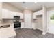 Modern kitchen featuring white cabinets, stainless steel appliances, granite countertops, and gray wood-look floors at 115 Frances St, Salisbury, NC 28147