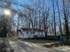 Quaint single-story home with a small porch surrounded by a canopy of tall, bare trees at 119 Lineberger St, Stanley, NC 28164