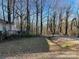 A property with mature trees along the road and a partial view of the house from the yard at 119 Lineberger St, Stanley, NC 28164
