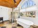 Bright bathroom with vaulted ceiling, claw foot tub, glass shower, stone tile, and large window at 1310 Woodland Dr, Charlotte, NC 28205