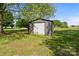 A backyard storage shed with light gray siding and a white roll-up door sits on a grassy lot in the yard at 139 Fort Dobbs Rd, Statesville, NC 28625
