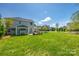 Spacious backyard with a lush lawn, stone barbecue, mature trees, and view of neighboring homes at 14905 Skyscape Dr, Huntersville, NC 28078