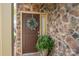 Elegant front door with stone surround, wreath, and potted plant for a welcoming entrance at 2001 Cramer Place Ct, Cramerton, NC 28032