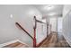 Bright hallway featuring wood floors and a wooden staircase with white trim and a view of a closed door at 2065 Taney Way, Indian Land, SC 29707
