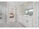 Bathroom featuring double sink vanity, white cabinets, large mirror, and a view to the main bedroom at 23112 Clarabelle Dr, Charlotte, NC 28273