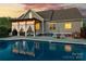 Backyard pool at dusk with pergola, string lights, and outdoor furniture, ideal for entertaining at 234 Deal Estate Dr, China Grove, NC 28023