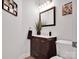 Powder room with a dark wood vanity, decorative mirror and neutral wall color at 2553 Fallbrook Nw Pl, Concord, NC 28027
