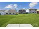 A large backyard featuring a lush green lawn, neighboring homes, and a concrete patio area at 2573 Blue Sky Meadows Dr, Monroe, NC 28110