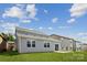 Back exterior view with neutral siding, windows, a sliding glass door and a well-maintained lawn at 2573 Blue Sky Meadows Dr, Monroe, NC 28110