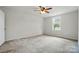 Bright bedroom featuring neutral carpet, a ceiling fan, and a sunlit window at 3619 Grove Creek Pond Sw Dr, Concord, NC 28027