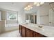 Bright main bathroom featuring double sinks, a soaking tub, and a separate glass shower at 3619 Grove Creek Pond Sw Dr, Concord, NC 28027