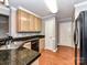 Efficient kitchen featuring black granite countertops, wood cabinets, and wood flooring at 4743 Morning Dew Ct # 4743, Charlotte, NC 28269