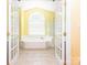 Bright bathroom featuring double doors, soaking tub, and large arched window at 6123 Glen Manor Dr, Charlotte, NC 28269