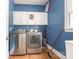 View of the laundry room, featuring a front-load washer and dryer, white storage cabinets, and blue painted walls at 6123 Glen Manor Dr, Charlotte, NC 28269