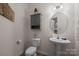 Well-lit powder room with a round mirror, pedestal sink, toilet, and a gray storage cabinet above the toilet at 637 Amber Meadows Way, Fort Mill, SC 29708