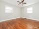 Bright bedroom featuring hardwood floors, a ceiling fan, and two windows at 7024 Rockledge Dr, Charlotte, NC 28210